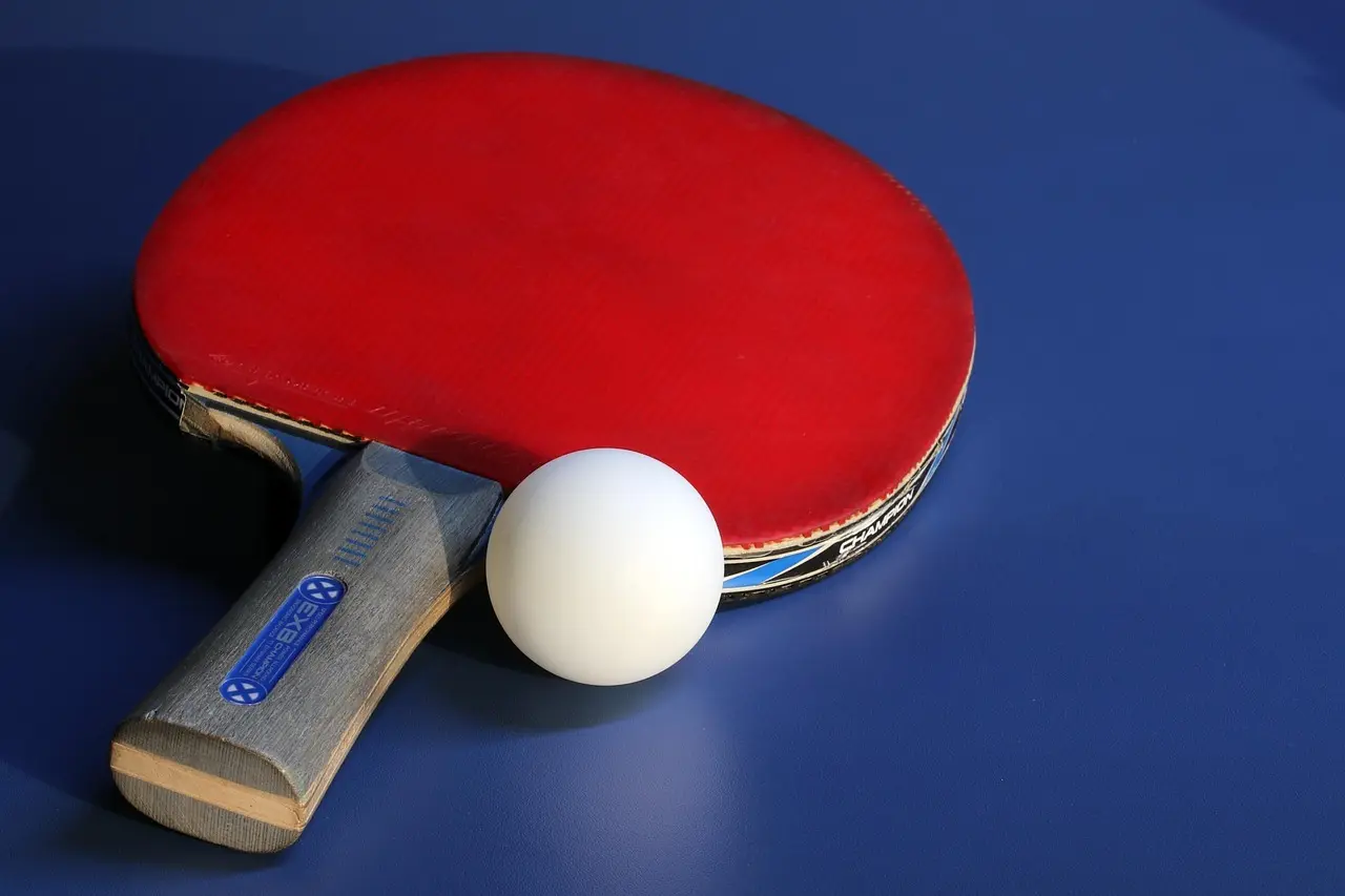 Bordtennisbat og bold på blåt bord